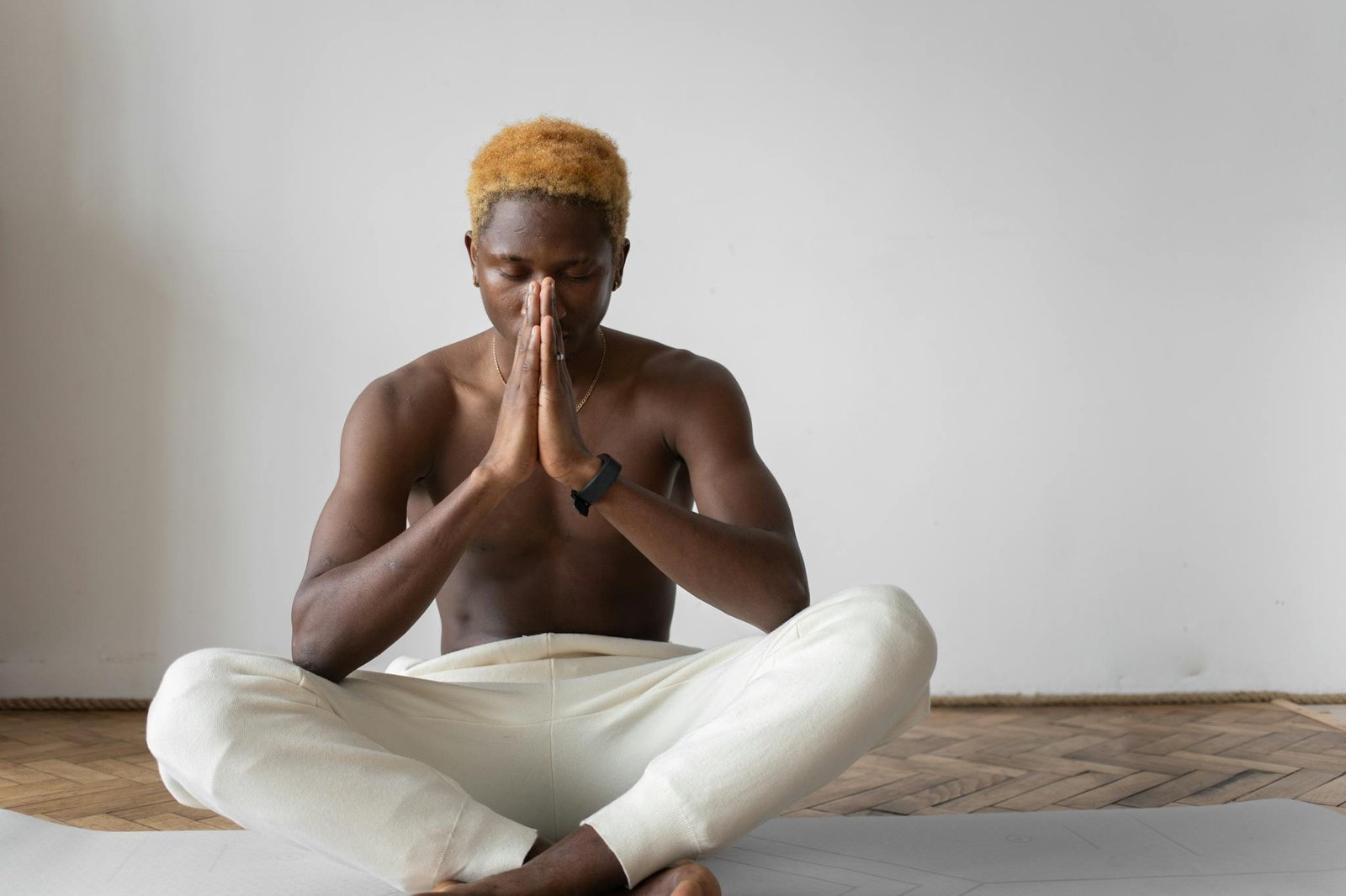 Peaceful meditation practice by a shirtless man in lotus position indoors.