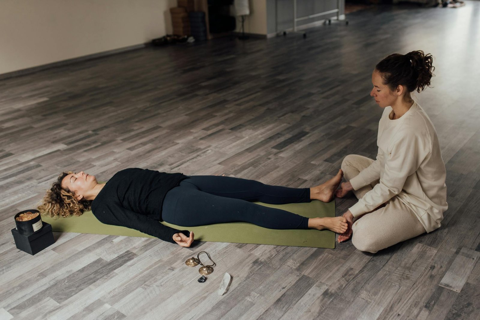 Two women engage in meditation and relaxation indoors, focusing on wellness and inner peace.